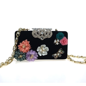 Detail of black velvet clutch with 3D fabric flowers, pearls, and a crystal butterfly clasp