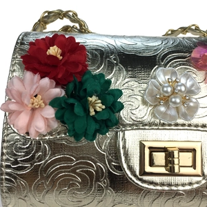 Close-up of champagne gold evening bag with rose embossing and 3D beaded floral detail