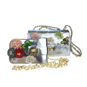 Detail of silver evening bag set featuring 3D fabric flowers and beaded chain strap