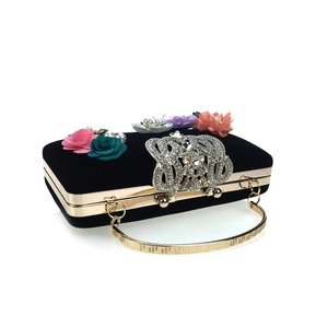 Detail of luxury velvet clutch bag featuring 3D satin flowers and rhinestone buckle