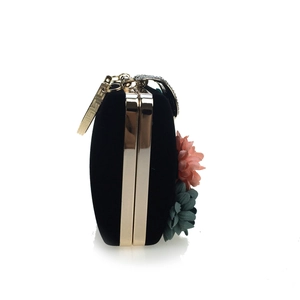Side view of black velvet evening clutch featuring 3D fabric flowers and gold metal trim
