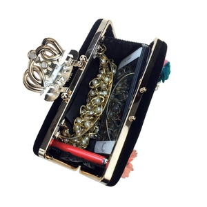 Detailed interior of black velvet evening bag with floral accents and crown clasp