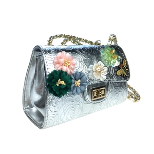 Detail of silver rose-embossed bag with 3D fabric flowers and golden bee clasp