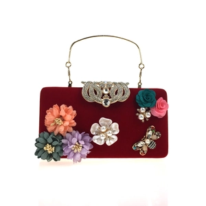 Detailed close-up of velvet clutch with 3D fabric flowers, pearls and a rhinestone bee