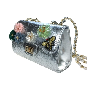 Detail of silver evening bag with 3D floral accents, bee embroidery and metal chain