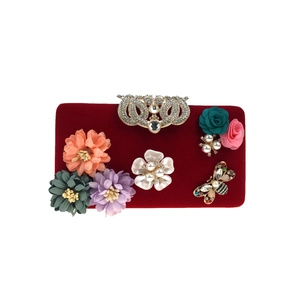 Macro detail of red velvet evening bag with 3D fabric flowers and crystal crown clasp