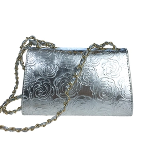 Detailed view of silver rose embossed evening bag with two-tone metal chain strap