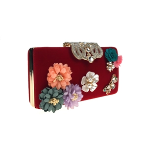 Detailed close-up of luxury red velvet evening bag with 3D fabric flowers and crystals