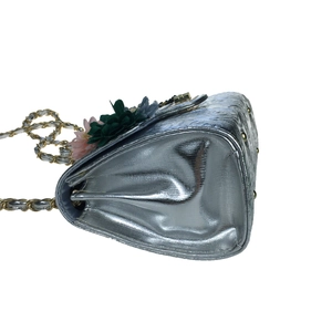 Detailed side view of silver evening bag with 3D floral accents and metal chain strap