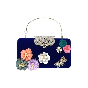 Detailed view of luxury navy velvet clutch with silk flowers, pearls and bee brooch