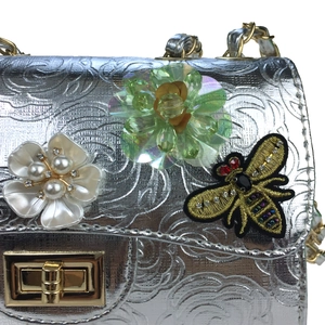 Detail of silver embossed roses with floral beads and bee patch on the evening bag