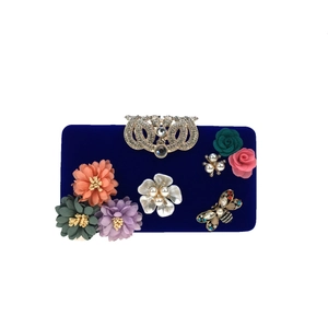 Detailed view of navy velvet clutch with 3D fabric flowers, pearls, and a crystal butterfly