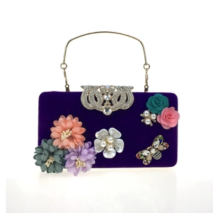 Detail of luxury purple velvet evening bag with 3D floral petals and jewel accents