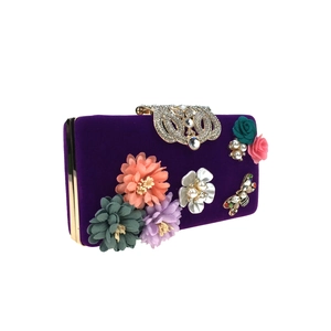 Detailed macro of purple velvet evening clutch with handmade floral 3D decor and crystals