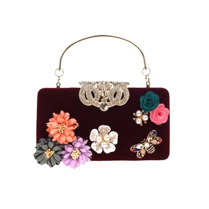 Close-up of velvet evening bag with 3D floral petals and crystal butterfly detail