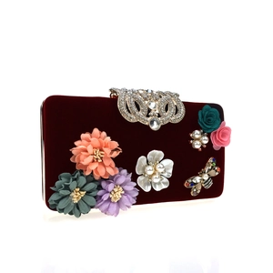 Close-up of velvet evening clutch with 3D floral petals and jewel-encrusted butterfly