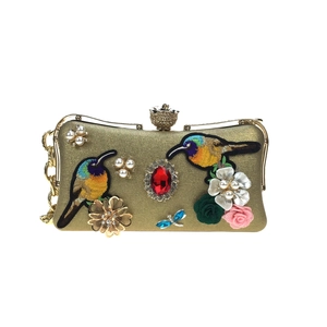 Luxurious gold evening clutch featuring bird embroidery, red ruby, and floral pearl accents