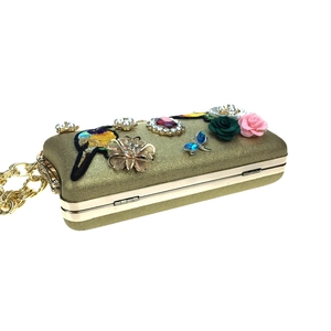 Detail view of gold evening clutch featuring bird embroidery and crystal flower embellishments