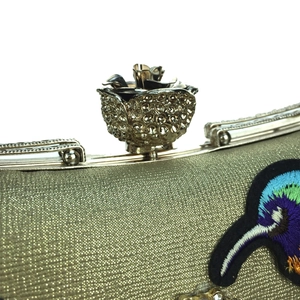 Detail of evening clutch featuring crystal flower clasp and colorful bird embroidery