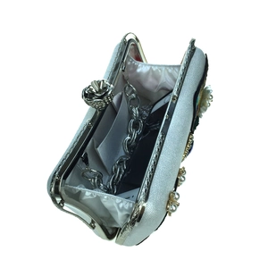 Interior view of white evening bag with pearl floral detail and chain strap for phone
