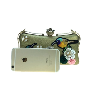 Detailed embroidery of birds and flowers on gold fabric evening clutch with pineapple clasp