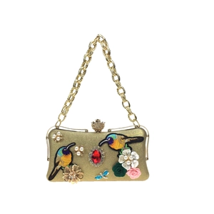 Detail of gold evening clutch with bird embroidery, pearl flowers and gemstones