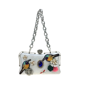 Detailed embroidery of colorful birds and gemstones on a white floral evening clutch bag