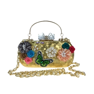 Détail du sac de soirée avec fleurs en satin 3D, papillon pailleté et fermoir cristal