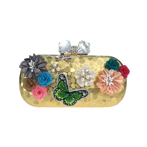 Détail d'une pochette de soirée florale avec pétales de soie, perles et broderie papillon