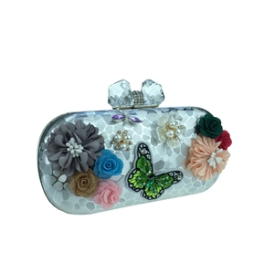 Détail de pochette de soirée argentée avec fleurs en relief et fermoir papillon