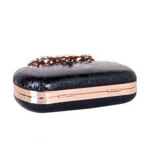 Detail of black textured evening clutch with rose gold frame and rhinestone flower clasp