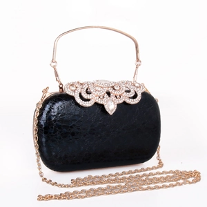 Detail of black evening clutch with rhinestone buckle, gold handle and metal chain