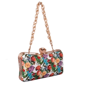 Macro shot of floral evening clutch featuring rose jewel clasp and gold metal chain