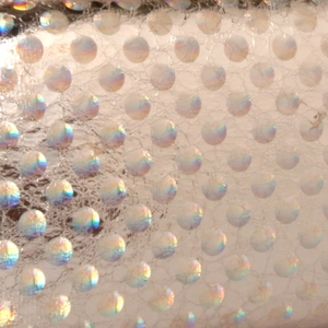 Macro shot of iridescent polka dot texture with silver mesh laser detail on evening bag