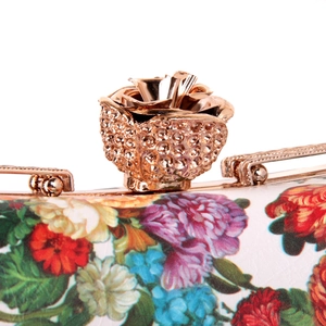 Detail of golden rose metal clasp and floral print on white leather evening clutch bag