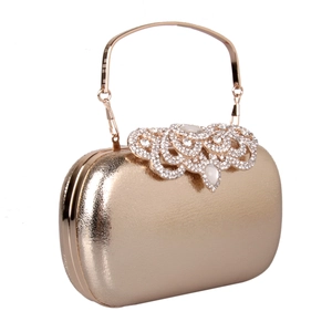 Close-up of golden evening clutch bag featuring rhinestone detailing and a metal handle