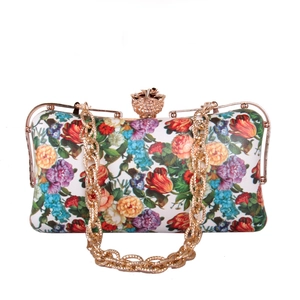 Macro shot of 3D gold flower clasp on a white floral print clutch bag with gold chain