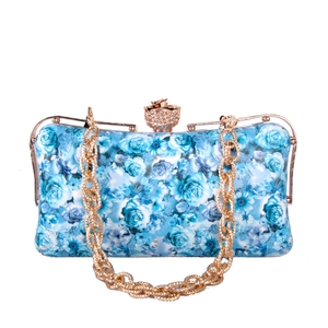 Detailed view of floral rose print clutch with crystal-encrusted flower clasp and gold chain