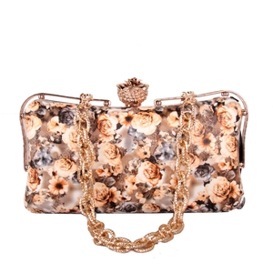 Detail of rose floral evening clutch with diamond-encrusted rose metal clasp and gold chain