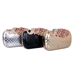 Hard shell evening clutch bags in silver, black, and gold with rhinestone peacock clasps