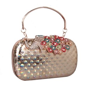 Detail of golden clutch bag with rhinestone peacock decor and rainbow laser texture