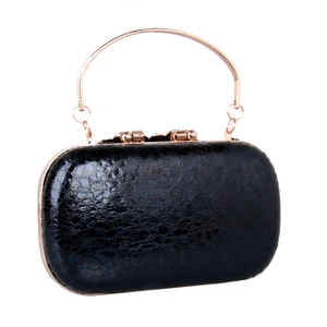 Detail of black cracked leather evening clutch with rose gold circular metal handle