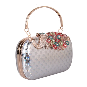 Close-up of holographic evening bag with crystal peacock motif and round metal handle
