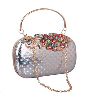 Detail of silver evening clutch featuring a colorful rhinestone peacock and gold handle