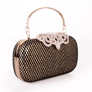 Détail d'une pochette de soirée avec grille dorée, fermoir strass et anse en métal