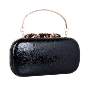 Close-up of black evening clutch with lace texture, metal handle, and rhinestone clasp