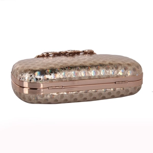 Close-up of champagne gold clutch with colorful sequins and diamond metal clasp