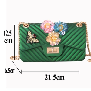 Detail view of green jelly crossbody bag with 3D floral accents and gold bee patch