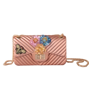 Detail of rose gold jelly crossbody bag with V-quilt texture and floral bee embellishments
