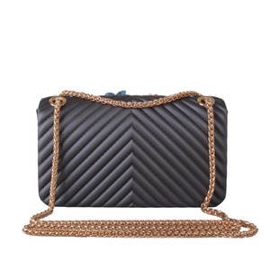 Detail of black silicone crossbody bag with V-shaped quilting and floral accents